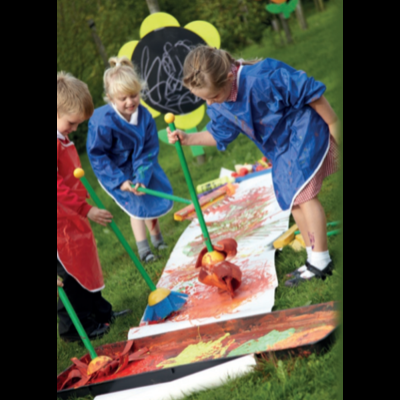 Crianças a pintar ao ar livre com aventais e grandes folhas de papel no chão