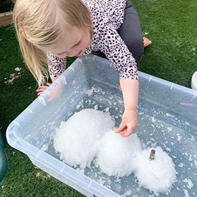 Recipiente plástico com bolas de neve de espuma e criança a brincar