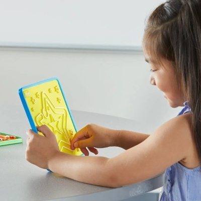 Criança a usar tabuleiro plástico amarelo com molduras de estrela e figuras em relevo