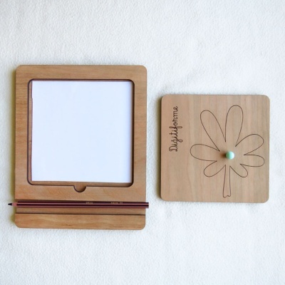 Moldura de madeira com papel e lápis, e placa de madeira com flor gravada