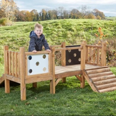 Parquinho infantil de madeira com painéis decorativos e rampa em relvado