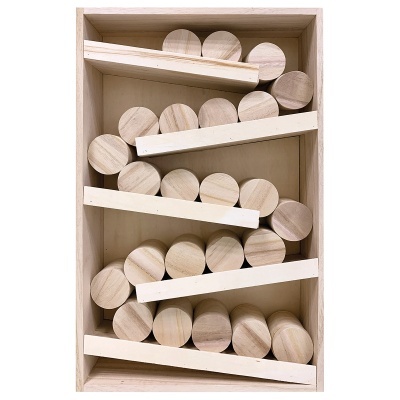 Caixa de madeira com bolas cilíndricas de madeira clara entre ripas brancas diagonais.