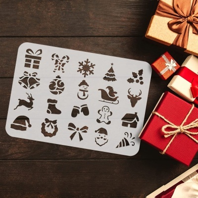 Cartão branco com recortes de motivos natalícios incluindo presentes, neve, Pai Natal, trenó, veado, ao lado de caixas de presente coloridas sobre madeira escura