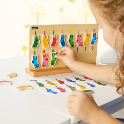 Jogo educativo de meias coloridas de madeira penduradas em fios em painel de madeira