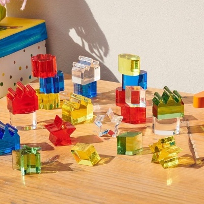 Blocos de construção translúcidos coloridos sobre mesa de madeira com caixa colorida ao fundo