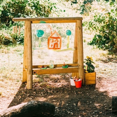 Painel transparente com desenhos coloridos numa estrutura de madeira ao ar livre