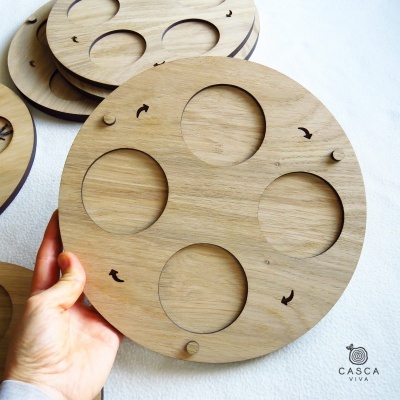 Disco redondo de madeira com recortes circulares e símbolos de peixes