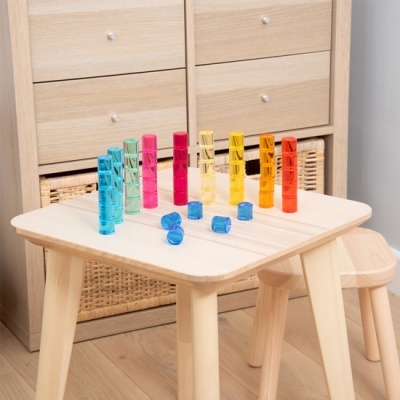 tubos plásticos coloridos sobre mesa de madeira clara com cadeira infantil