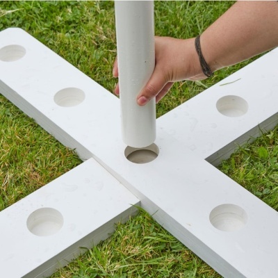 Base branca cruzada com tubo branco encaixado em relva verde