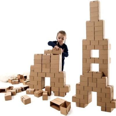 Criança a empilhar blocos de madeira castanhos formando torres em fundo branco