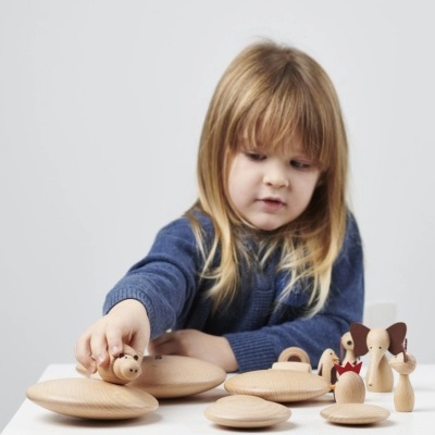 Brinquedos de madeira naturais com figuras humanas e discos, criança loira a brincar