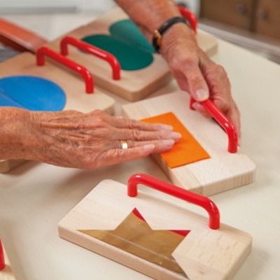 Blocos de madeira com formas coloridas e alças vermelhas sobre mesa clara