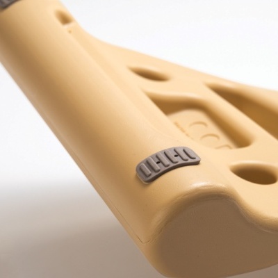 Estrutura plástica bege com peça cinzenta e sulcos, sobre fundo branco