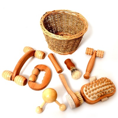 Conjunto de acessórios de madeira para massagem e cesto redondo em palha sobre fundo branco