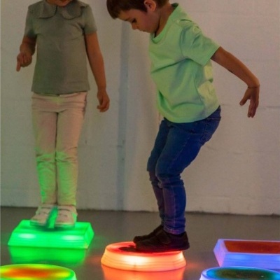 Crianças brincando com blocos de luz colorida no chão