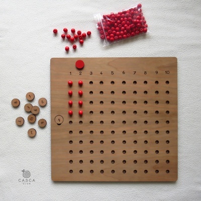 Jogo educativo de madeira com tabuleiro quadrado, bolinhas vermelhas e discos numerados de madeira