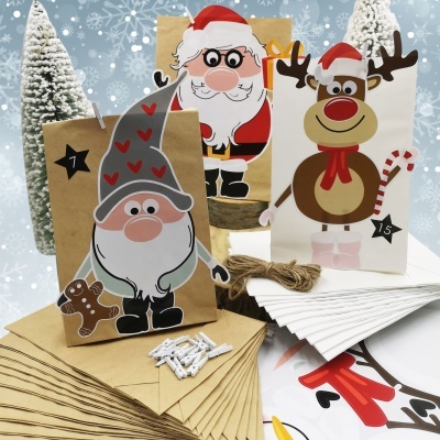 Sacos de papel natalícios com ilustrações de duende, Pai Natal e rena, envelopes e molas para decoração.