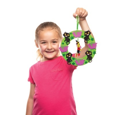 Criança com t-shirt rosa segura coroa decorativa verde com gatinhos e palhaço