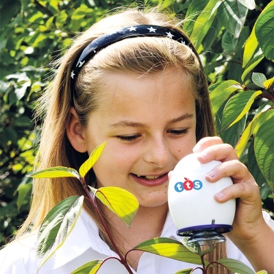 Menina com dispositivo branco TTS junto a planta verde e amarela num ambiente exterior