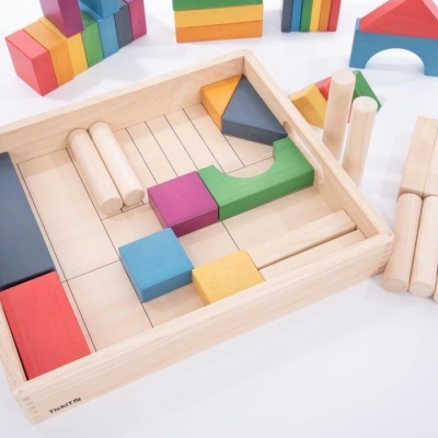 Blocos de construção de madeira coloridos numa caixa de madeira sobre superfície branca