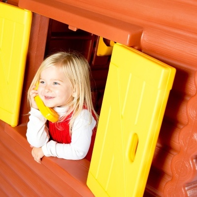 Menina a brincar numa casinha de plástico com janelas amarelas abertas