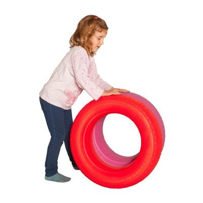 Menina com camisola rosa clara e calças azuis a segurar pneu vermelho grande