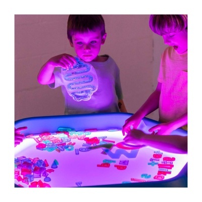 Crianças a brincar com tabuleiro iluminado e peças coloridas de plástico