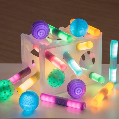 Cubo translúcido com barras coloridas luminosas e bolas texturizadas coloridas.