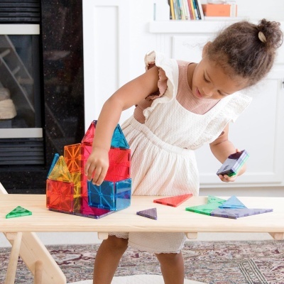 Menina a brincar com blocos de construção coloridos numa mesa em casa