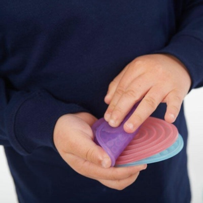 Mãos de criança a segurar brinquedo flexível de silicone roxo, rosa e azul