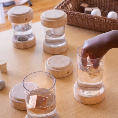 Acessórios de vidro e madeira clara sobre mesa com água e cubos