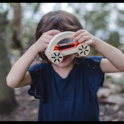 Criança a brincar com brinquedo de carro de madeira ao ar livre