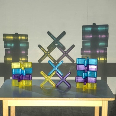 Peças de plástico coloridas em forma de x sobre uma mesa de madeira clara