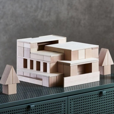 Blocos de madeira natural empilhados em forma de estrutura com duas figuras triangulares ao lado