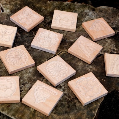 Blocos quadrados de madeira com flores gravadas em relevo sobre pedra escura