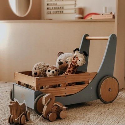 Carrinho de madeira com peluches e brinquedos de madeira num quarto claro