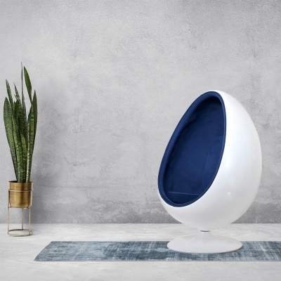 Cadeira cápsula branca com interior azul escuro e planta em vaso dourado