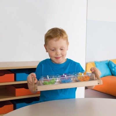 Criança loira com camisola azul segura bandeja com bolinhas coloridas