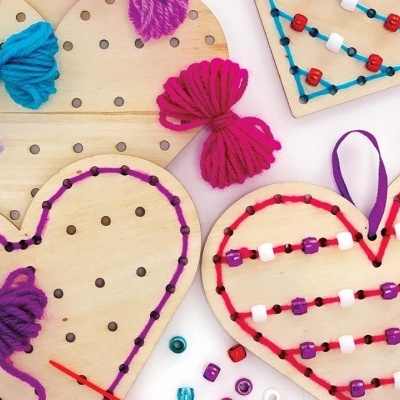 Painéis de madeira em forma de coração com fios de lã colorida e contas