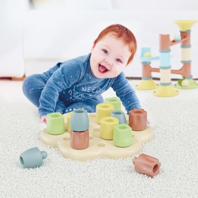 Bebé a brincar com brinquedos de encaixe coloridos sobre carpete branca