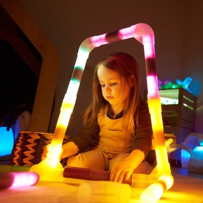 Criança a brincar com tubos de luz coloridos no chão