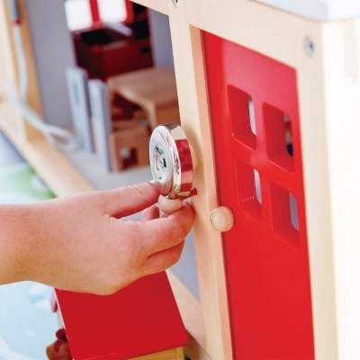 Mão de criança girando maçaneta em porta vermelha de madeira de brinquedo