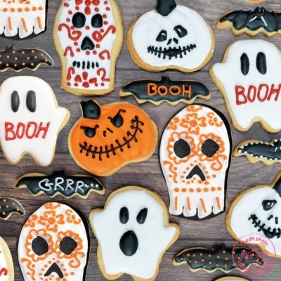 Biscoitos decorados de Halloween com fantasmas, abóboras, crânios e morcegos coloridos sobre madeira