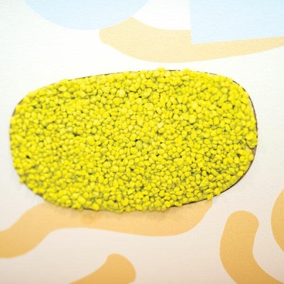 Tapete antiderrapante amarelo de pequenas esferas sobre superfície com padrões coloridos