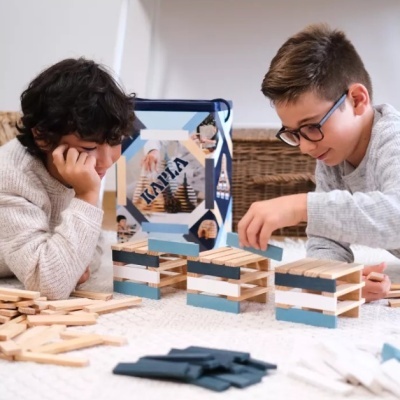 Crianças a jogar com blocos de madeira empilhados em azul, branco e castanho claro