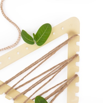 Estrutura amarela com cordas de juta e duas folhas verdes sobre fundo branco