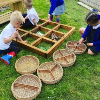 Crianças brincam com estrutura de madeira e cestas de vime na relva