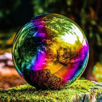 Esfera de vidro iridescente colorida sobre musgo em ambiente natural