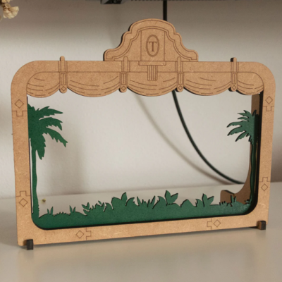 Espelho com moldura de madeira clara decorada com árvores verdes e vegetação.