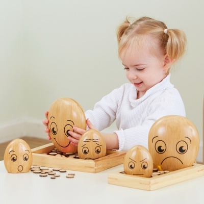 Criança a brincar com bonecos de madeira com expressões faciais